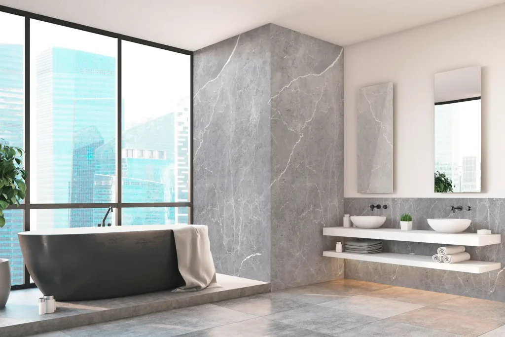 Badezimmer mit schwarzer Wanne links und weißen Waschtischen rechts, hellgraue Rückplatten in Steinoptik an den Wänden