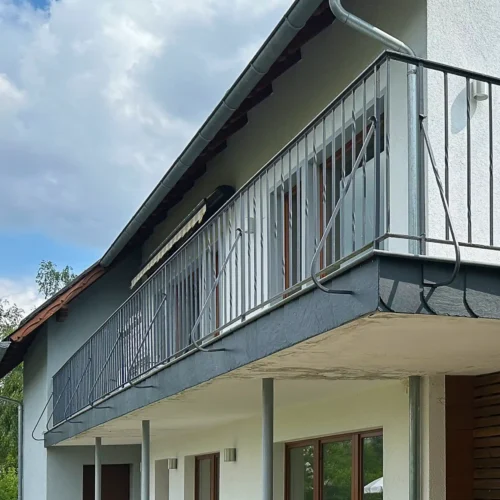 Blick von unten zum Balkon vor der Balkonsanierung: Metallgeländer, Schieferplatten an der Kante