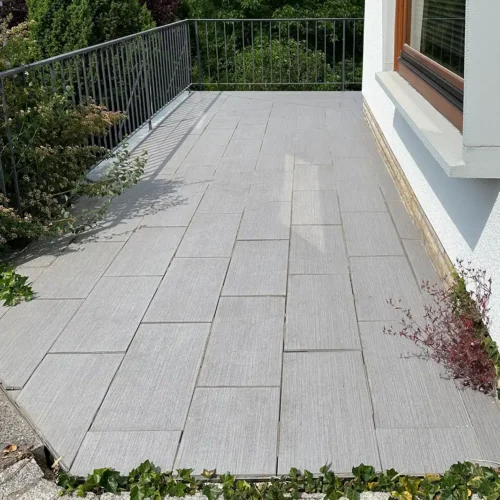 Boden des Balkons vor der Balkonsanierung mit alten hellgrauen rechteckigen Fliesen mit Längsmaserung