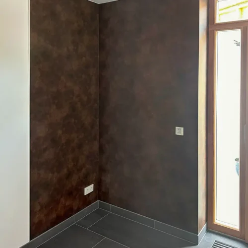 dunkelbraune fugenlose Wandverkleidung, links weiße Wand, rechts Eingangstür