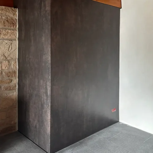 dunkelbraune fugenlose Wandverkleidung, links gemauerte Wand, rechts weiße Wand